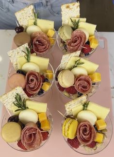 four glasses filled with different types of cheese and meats on top of each other