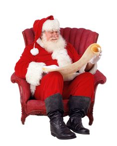 a man dressed as santa claus sitting in a red chair reading a paper with his legs crossed