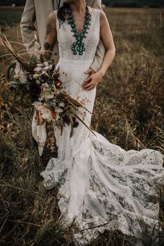 a bride and groom are standing in the tall grass