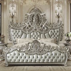 an ornate white bed in a fancy bedroom with chandelier and flowers on the table