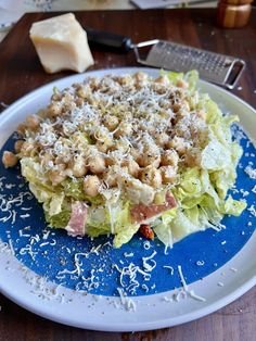 a blue plate topped with lettuce and meat covered in parmesan cheese