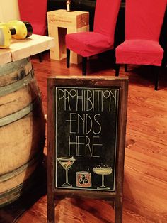 a sign that says prohibition ends here next to some wine barrels and red chairs in the background