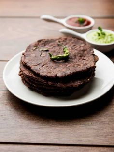 a stack of tortillas sitting on top of a white plate next to dipping sauce