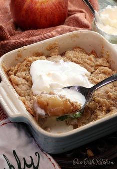 an apple crisp in a baking dish with a spoon and yogurt on top