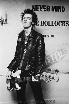 a black and white photo of a man with a guitar in front of a poster