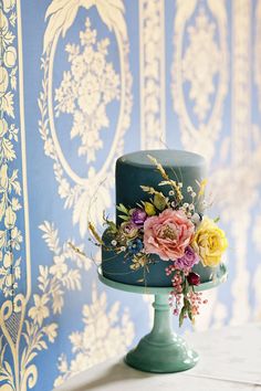 there is a blue cake with flowers on it