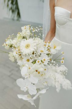 a bride holding a bouquet of white flowers