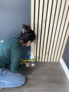 a woman kneeling down on the floor with a screwdriver