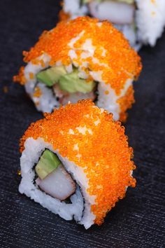 sushi rolls with avocado and cucumber are on a black plate