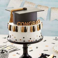 a graduation cake that is decorated with gold and black tassels on top of it