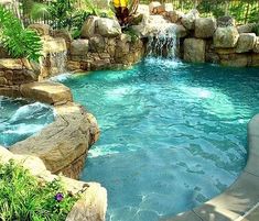 an outdoor swimming pool with waterfall and rocks