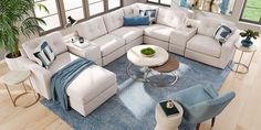 a living room filled with white furniture and blue rug on top of a hard wood floor