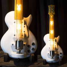 two white electric guitars with yellow lights on their heads and neck, sitting side by side