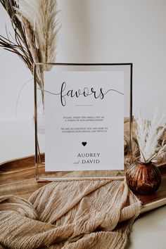 a sign that says favors on it next to some dried plants and a vase with flowers