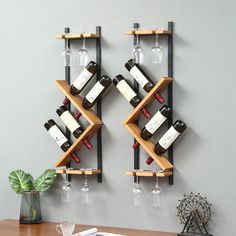 two wooden shelves holding wine bottles and glasses on top of a table next to a plant