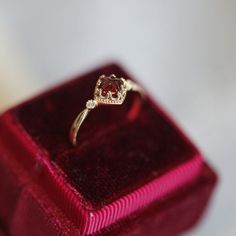 a diamond ring sitting on top of a red velvet box with its reflection in it