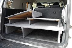 the back end of a white van with two shelves in it's trunk area