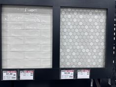 two black and white boxes with price tags on them in front of a tiled wall