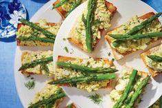 asparagus and eggs on toasted bread are arranged on a white platter