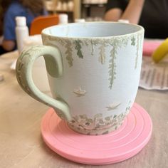 a coffee cup sitting on top of a pink coaster