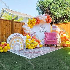 an outdoor birthday party with balloons and decorations on the grass, in front of a fence