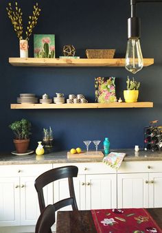 a kitchen with two shelves on the wall and a dining room table in front of it