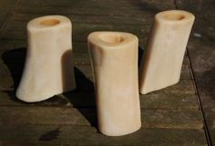 three white candles sitting on top of a wooden table