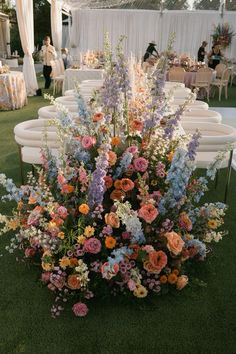 an arrangement of flowers is on the ground at a wedding reception with white linens