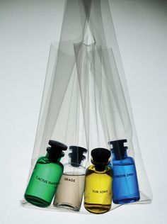 three different colored bottles are sitting in a clear bag on a white surface, one is blue and the other is green