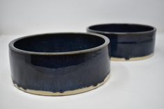 two black bowls sitting next to each other on a table