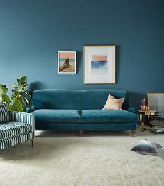 a living room with blue walls and white carpeted flooring, two couches in front of a large painting on the wall