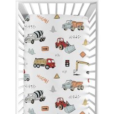 a baby crib with trucks and construction vehicles on the bedding, in white