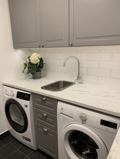 a washer and dryer sitting in a kitchen next to a counter with flowers on it