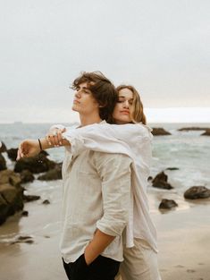 a man and woman are standing on the beach