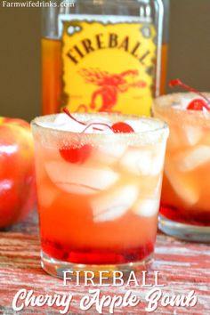 two glasses filled with fruit and ice sitting on top of a table next to an apple