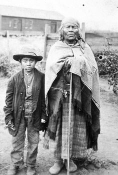 an old black and white photo of two men standing next to each other in the dirt