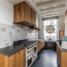 a kitchen with wooden cabinets and black counter tops, along with a large clock on the wall