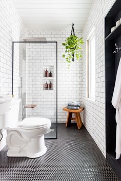 a white toilet sitting next to a shower in a bathroom with black and white tiles