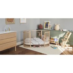 a baby's room with a crib, dresser and bed in the corner