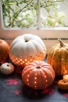 some pumpkins are sitting next to each other on a table in front of a window