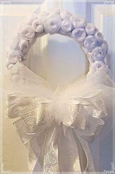 a white wreath with flowers on the front and side of it hanging from a door