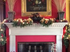 a mantel decorated with christmas wreaths and candles in front of a fire place