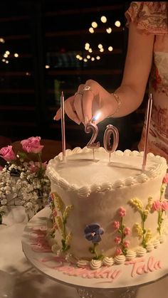 a woman holding a lit candle in front of a cake with the number 30 on it