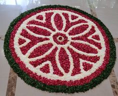 a circular flower arrangement on the floor with red and white flowers in it's center