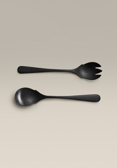 two spoons with black handles on a gray background, one has a fork and the other is a spoon