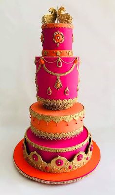 a three tiered pink and orange cake with gold decorations on it's sides