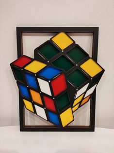 a rubik cube in a wooden frame on a white surface with one side missing