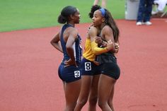 three female athletes are huddled together on the track