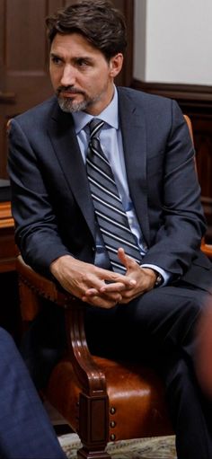 a man sitting in a chair wearing a suit and tie