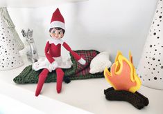 an elf sitting on top of a blanket next to a fire